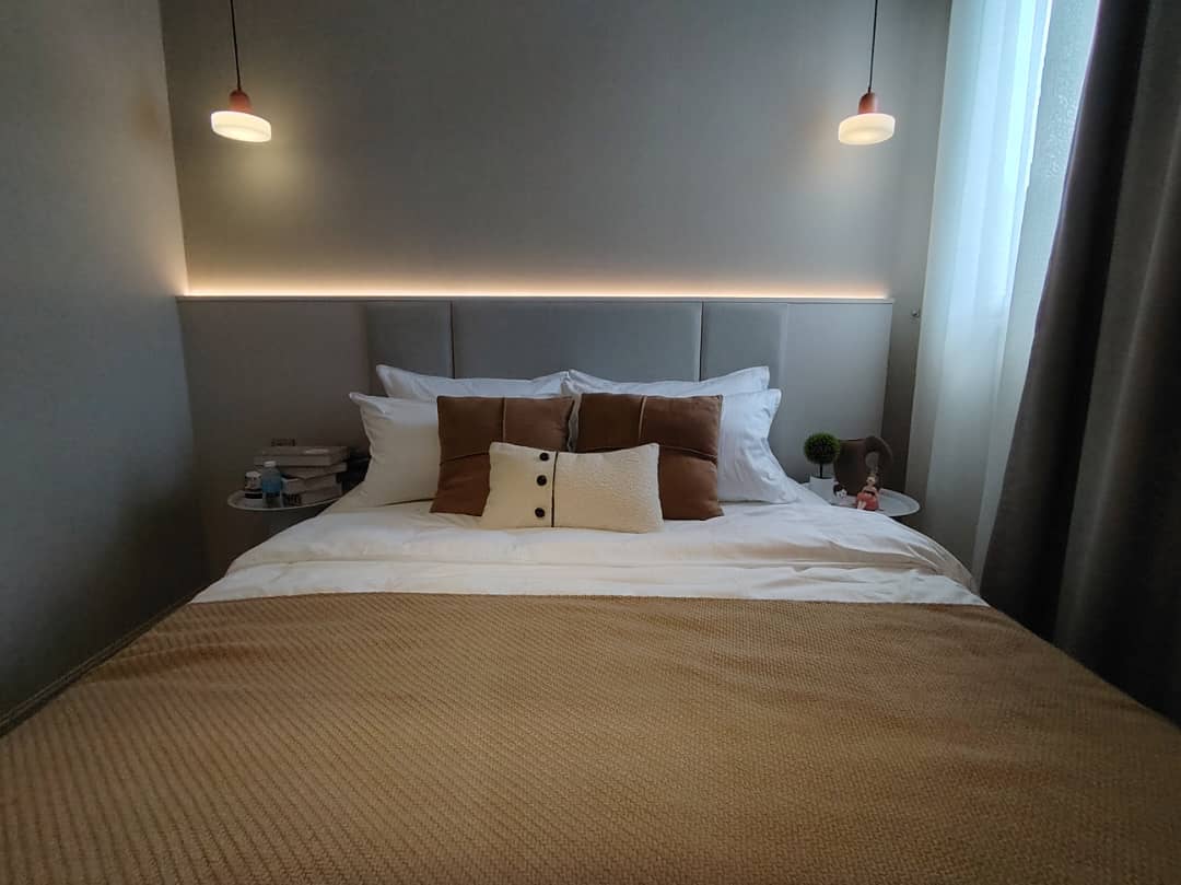 Master bedroom with hotel-style pendant lights and upholstered headboard